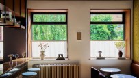 Stylish interior of Hotel Petra Copenhagen with bar stools, window views of lush trees, and chic seating.