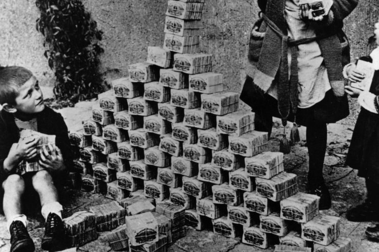 Children playing with stacks of German Mark banknotes during hyperinflation in 1920s Germany, illustrating economic crisis.