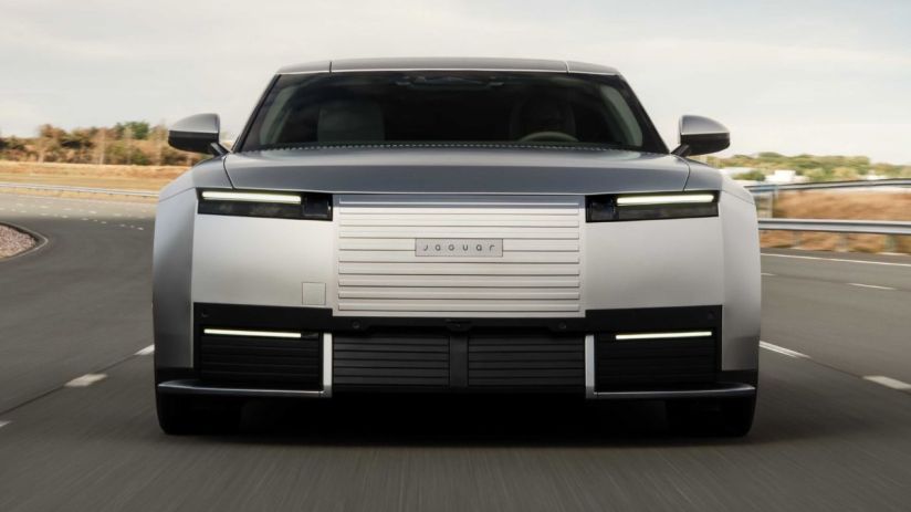 Front view of a modern gray Jaguar car with distinctive headlights and grille on a highway