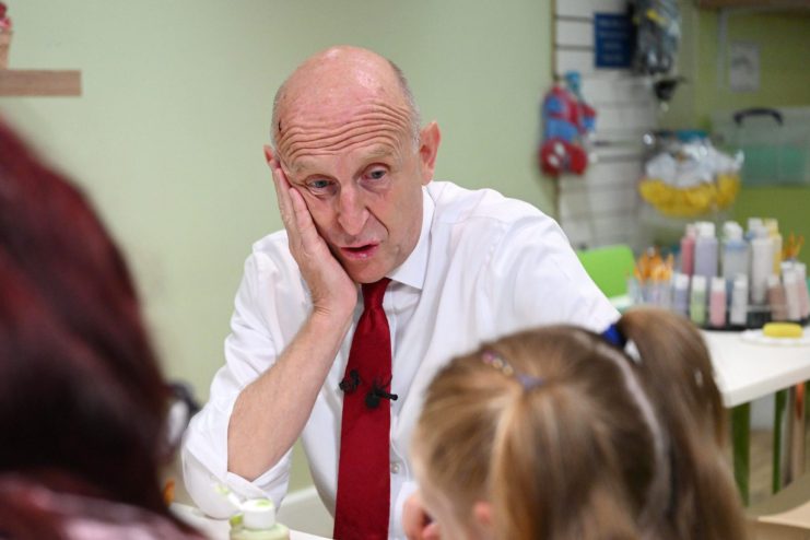 John Healey, MP, at a table with a woman and child, looking concerned about inflation