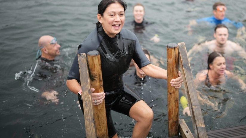 Lisa Nandy in a wetsuit climbing out of the water at Labour Party Conference 2026, smiling with other swimmers.