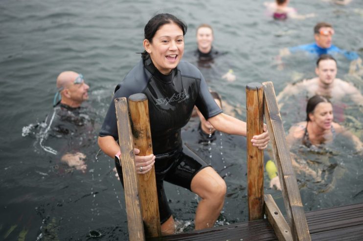 Lisa Nandy in a wetsuit climbing out of the water at Labour Party Conference 2026, smiling with other swimmers.