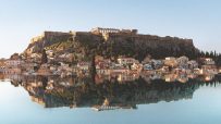 Acropolis of Athens and historic Plaka neighborhood reflected in calm water, ideal literary stay in Greece.