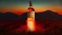 Monkey Shoulder blended malt Scotch whisky bottle on a glowing red pedestal at sunset