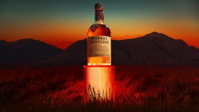 Monkey Shoulder blended malt Scotch whisky bottle on a glowing red pedestal at sunset