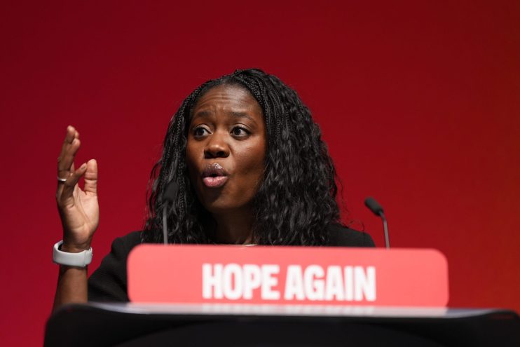 Miatta Fahnbulleh speaking at a podium with HOPE AGAIN visible, gesturing with her right hand.