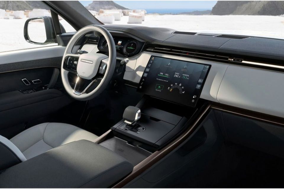 Modern Range Rover interior with steering wheel, digital dashboard, and infotainment screen showing charge and range