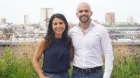 Relace co-founders Lyubomira Dimitrova and Justin Peimani smiling on a rooftop garden with city buildings in background