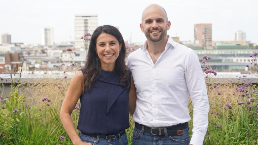 Relace co-founders Lyubomira Dimitrova and Justin Peimani smiling on a rooftop garden with city buildings in background