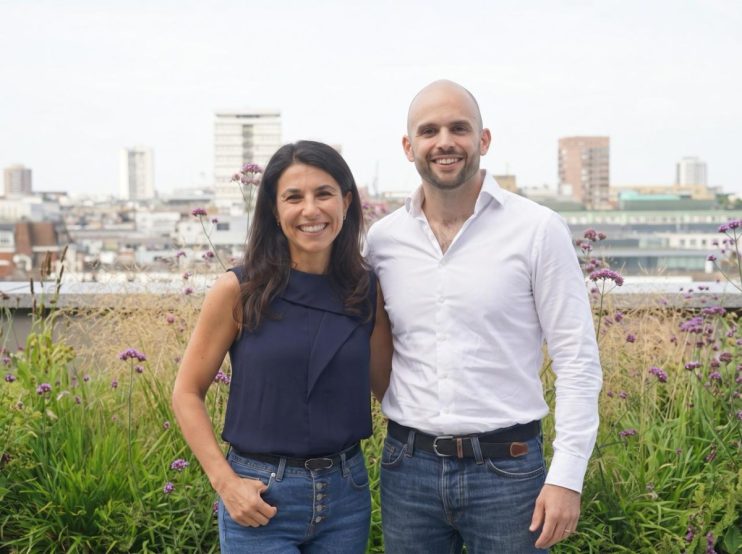 Relace co-founders Lyubomira Dimitrova and Justin Peimani smiling on a rooftop garden with city buildings in background
