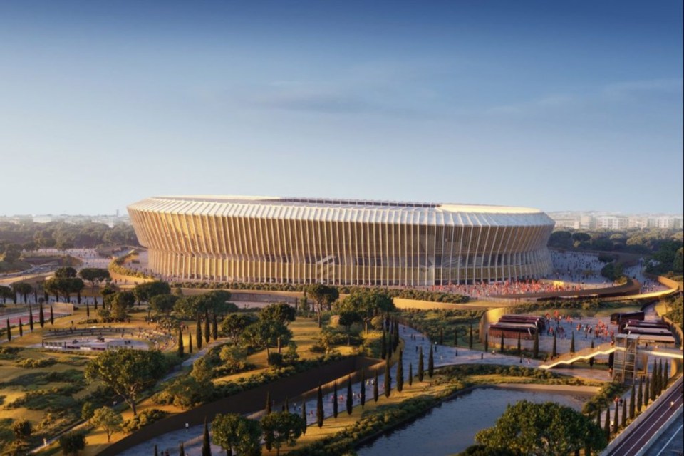 Aerial view of a modern, large stadium with golden vertical fins, surrounded by green parkland and a river.