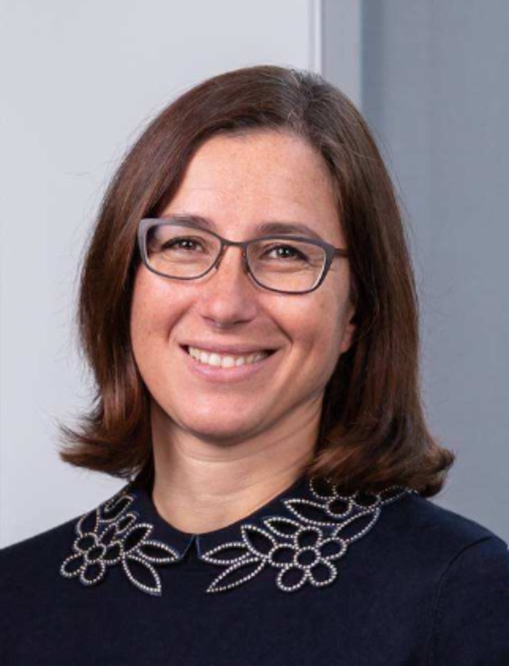 Professional headshot of Sandra smiling, wearing glasses and a dark top with an embellished collar.