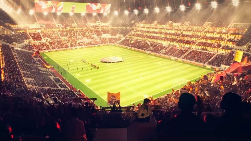 Packed football stadium at night, bright green field, fans cheering, scoreboard visible, sports event atmosphere.