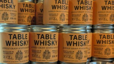 Rows of Table Whisky single grain Scotch jars with orange labels, distilled in Edinburgh.