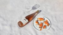 Sober October ros&eacute; wine bottle next to a wine glass and crackers with cream cheese and caviar on a white cloth