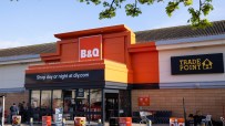 Exterior view of a B&Q store entrance with Shop day or night at diy.com and Trade Point signage.