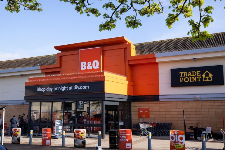 Exterior view of a B&Q store entrance with Shop day or night at diy.com and Trade Point signage.