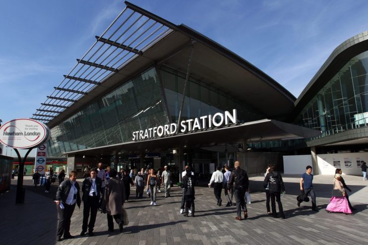 Stratford Station exterior with modern glass architecture and pedestrians on a sunny day
