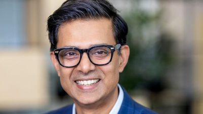 Suresh Balaji, a smiling man in glasses and a blue plaid suit jacket, looking at the camera.