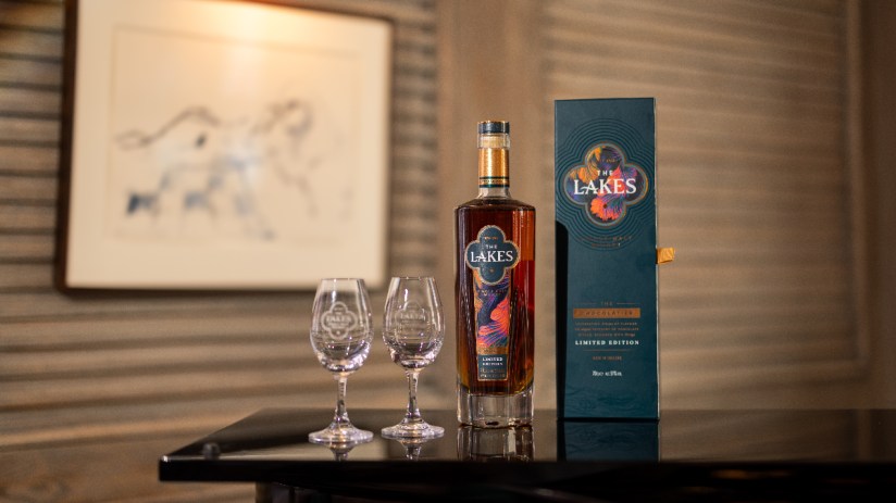 The Lakes Chocolatier limited edition whisky bottle, two branded glasses, and gift box on a dark surface