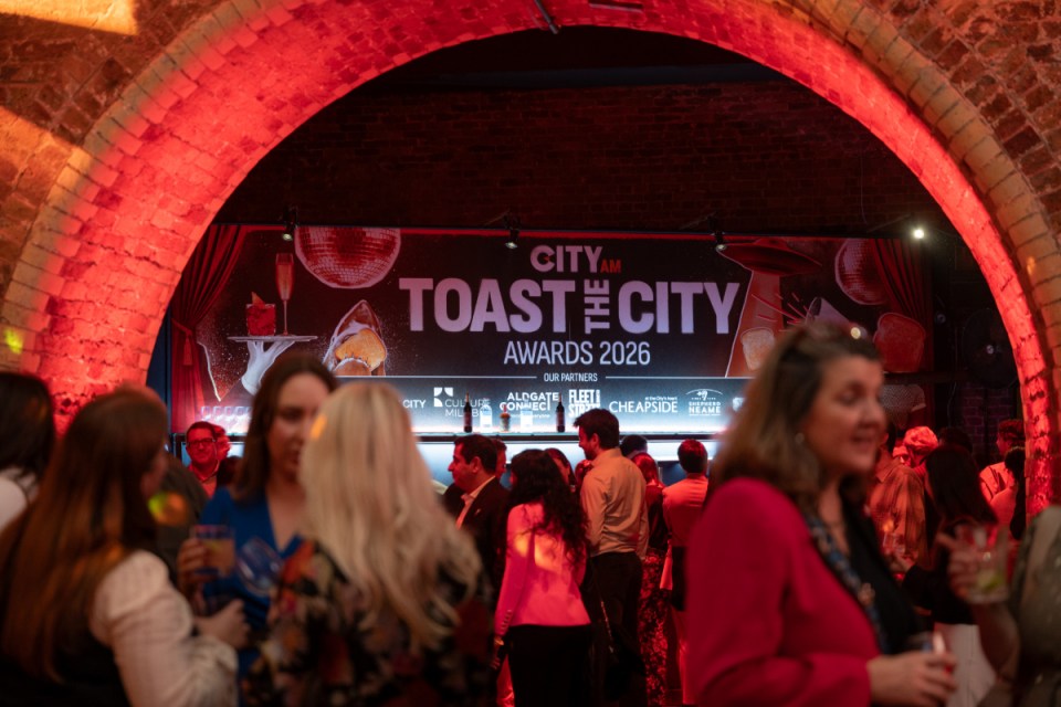Guests mingling under a red-lit brick archway at the City AM Toast the City Awards 2026 event.