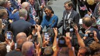 Kemi Badenoch and Kwasi Kwarteng smiling, surrounded by a crowd holding up phones and Union Jack flags at the Tory confere...