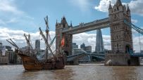 Historic ship sailing past Londons Tower Bridge and The Shard skyscraper on the River Thames.