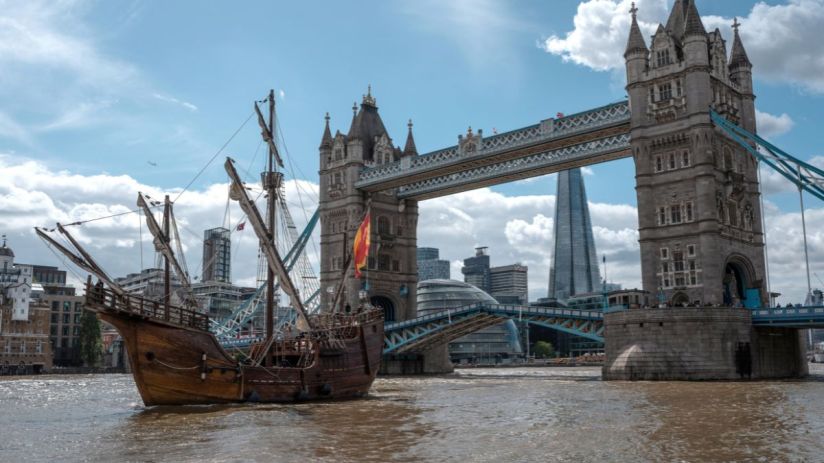 Historic ship sailing past Londons Tower Bridge and The Shard skyscraper on the River Thames.