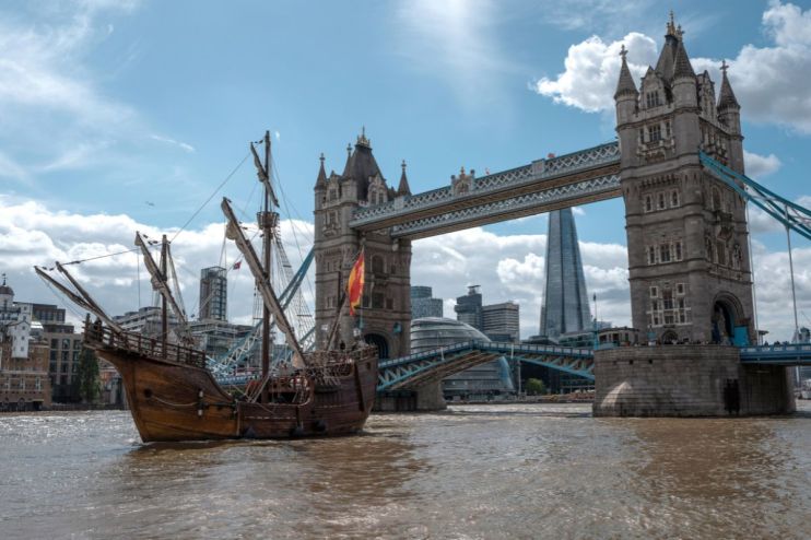 Historic ship sailing past Londons Tower Bridge and The Shard skyscraper on the River Thames.