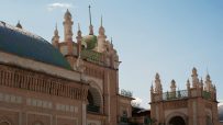 Ornate Uzbek architecture with a tiled dome and decorative brickwork under a clear sky, Silk Road travel.