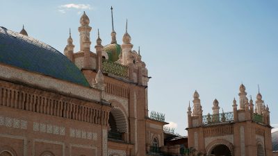 Ornate Uzbek architecture with a tiled dome and decorative brickwork under a clear sky, Silk Road travel.
