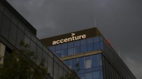 Accenture office building facade with logo visible against a dark, cloudy sky.