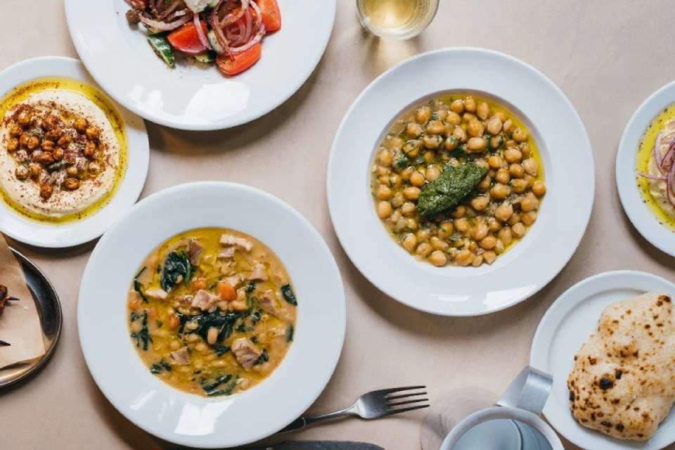 A delicious spread of Greek and Mediterranean dishes including hummus, salad, stews, and flatbread.
