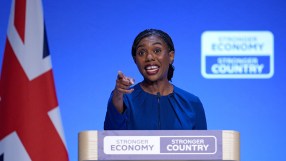 Kemi Badenoch, a politician, speaks at a podium with a Union Jack flag and Stronger Economy, Stronger Country signs.