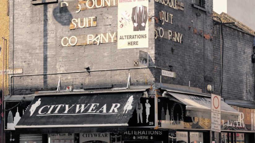 Discount Suit Company building with Alterations Here banner, Citywear awnings, and street signs for Wentworth St. and Bell...