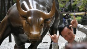 Wall Street Charging Bull statue with a man smiling and making shaka gestures in front of it