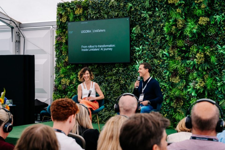 Two speakers, a woman and a man, on stage discussing Linklaters AI journey in front of an audience.