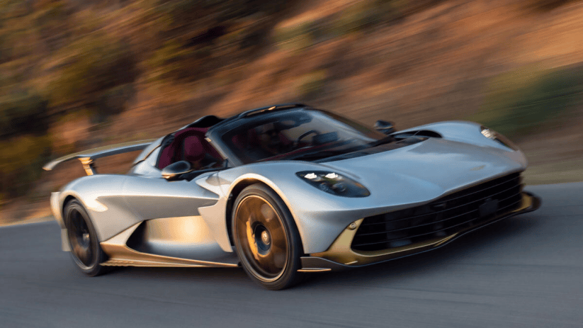 Silver sports car with gold accents speeding on a road, motion blur in background