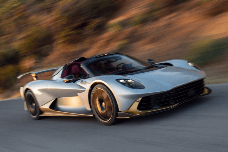 Silver sports car with gold accents speeding on a road, motion blur in background