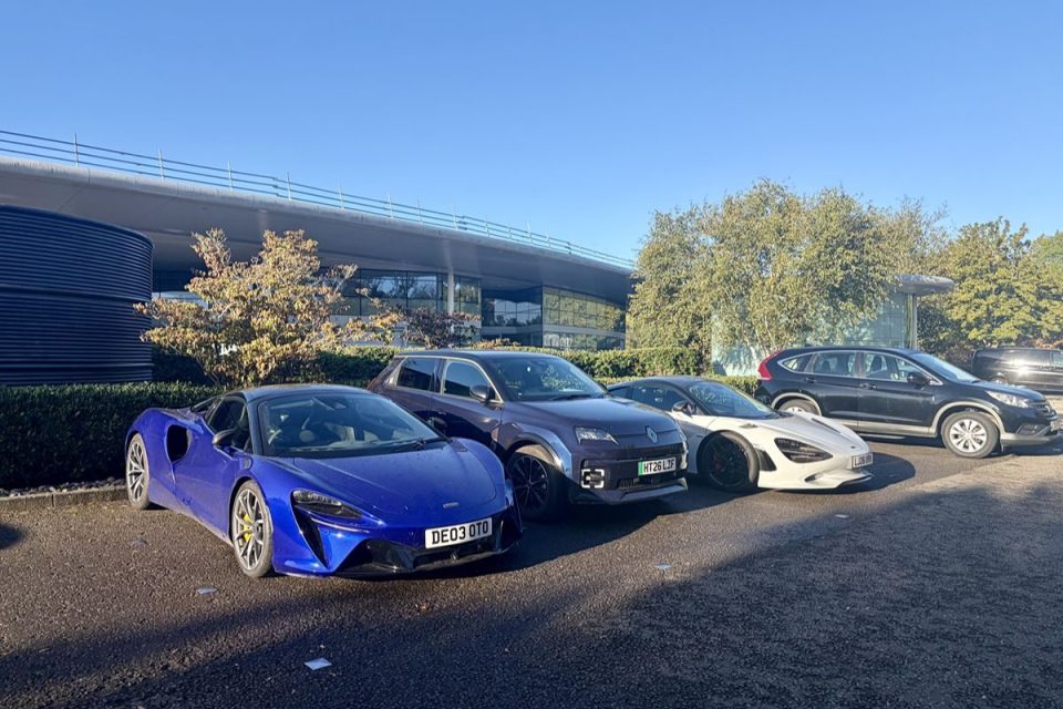 Luxury cars parked outside a modern business building on a sunny day
