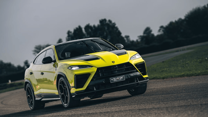 Bright yellow Lamborghini Urus SE SUV on a wet asphalt road, dark sky and trees in background