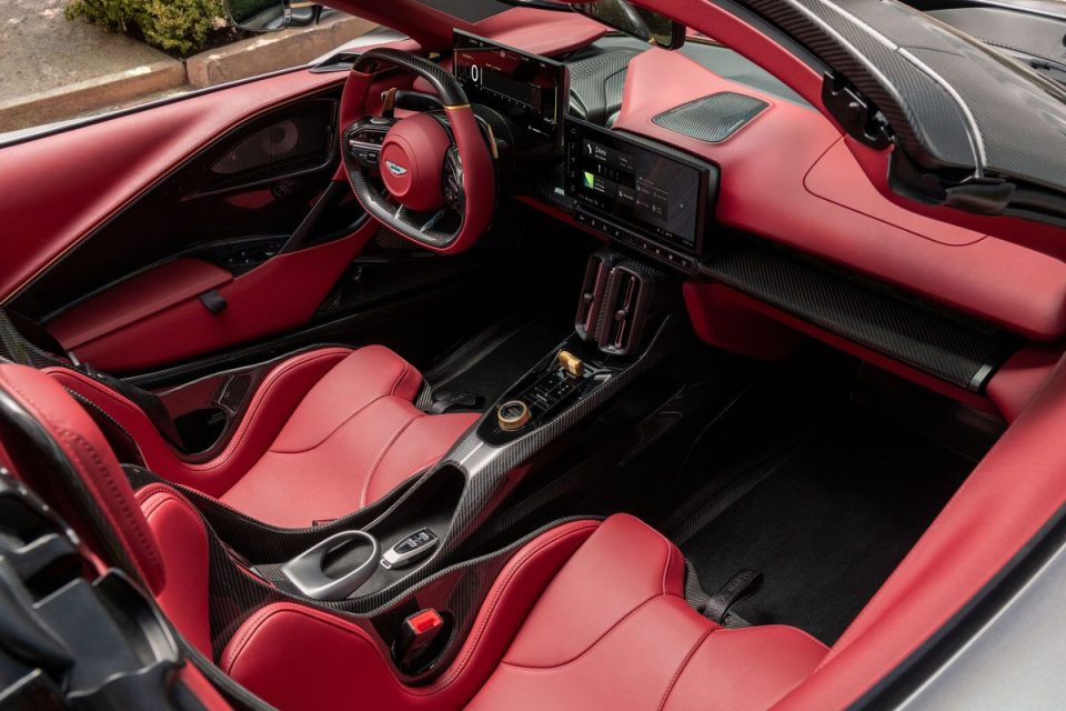 Luxury car interior with red leather seats, carbon fiber accents, and a modern dashboard display.