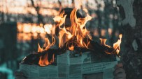 Hands holding a burning newspaper, symbolizing information wars and local news on fire