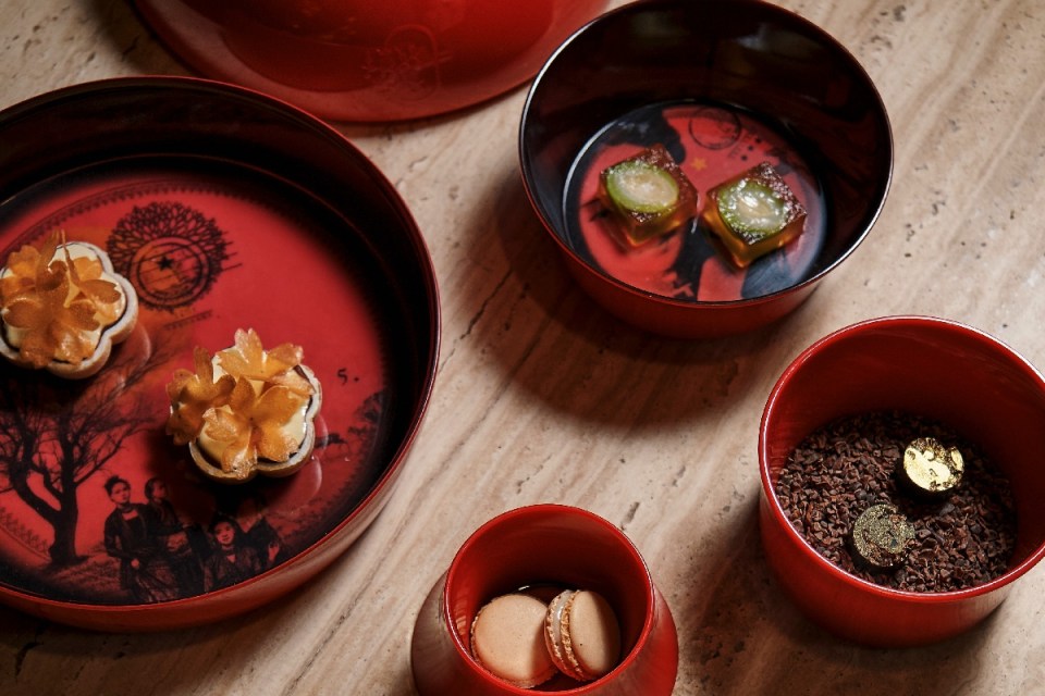 Assortment of gourmet desserts in red decorative bowls on a stone surface