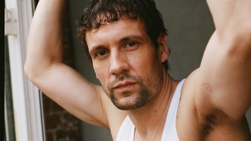 Nick Blood, an actor, looking directly at the camera while wearing a white tank top.