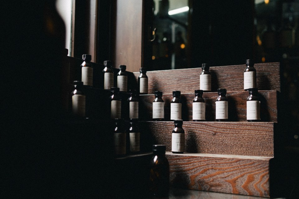 Small amber bottles with white labels, possibly Omoda 7 scents, displayed on dark wooden steps
