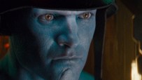 Close-up of a blue-skinned man with intense brown eyes and a dark helmet, depicting a rogue trooper character