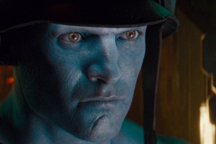 Close-up of a blue-skinned man with intense brown eyes and a dark helmet, depicting a rogue trooper character
