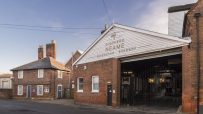 Shepherd Neame Faversham Brewerys brick building with white gable sign, next to a traditional brick house.