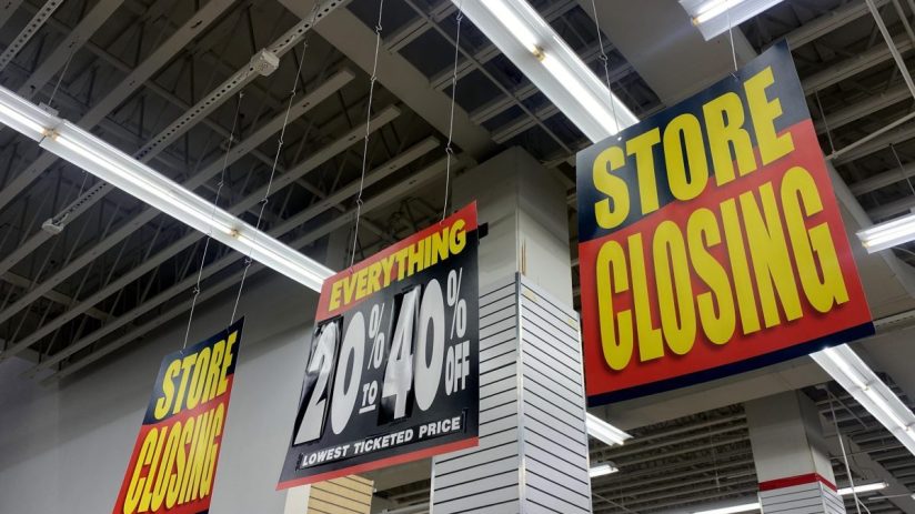 Store Closing signs and a 20% to 40% Off sale sign hanging inside a retail store.